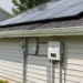 Solaranlage auf einem Hausdach mit Photovoltaikmodulen und Wechselrichter an der Hauswand.